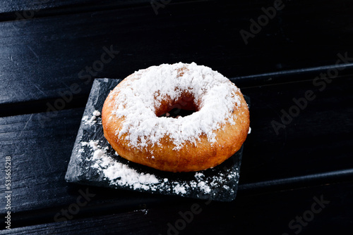 Delicious donuts with powdered sugar on wooden table