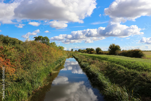 landscape with river and blue sky, cloud reflection in the water, early autumn in the countryside