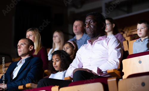 Father and daughter carefully watch spectacle in the theater hall
