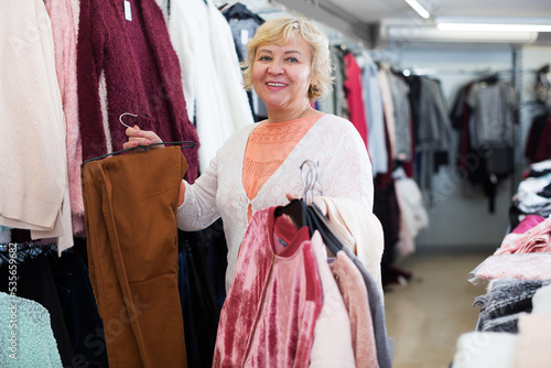 smiling buyer choosing clothes on hanger in the dress shop