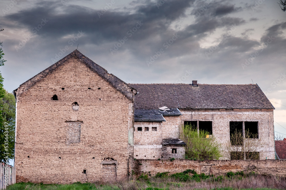 Old windows and a crumbling facade on an abandoned residential building of a farm in Ruma, Vojvodina, Serbia, with a damaged and decaying facade.... Old windows and a crumbling facade on an abandoned residential building of a farm in Ruma, Vojvodina, Serbia, with a damaged and decaying facade....