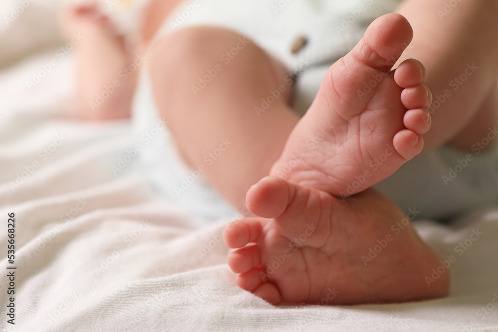 Cute newborn baby lying on bed, closeup of legs. Space for text Cute newborn baby lying on bed, closeup of legs. Space for text