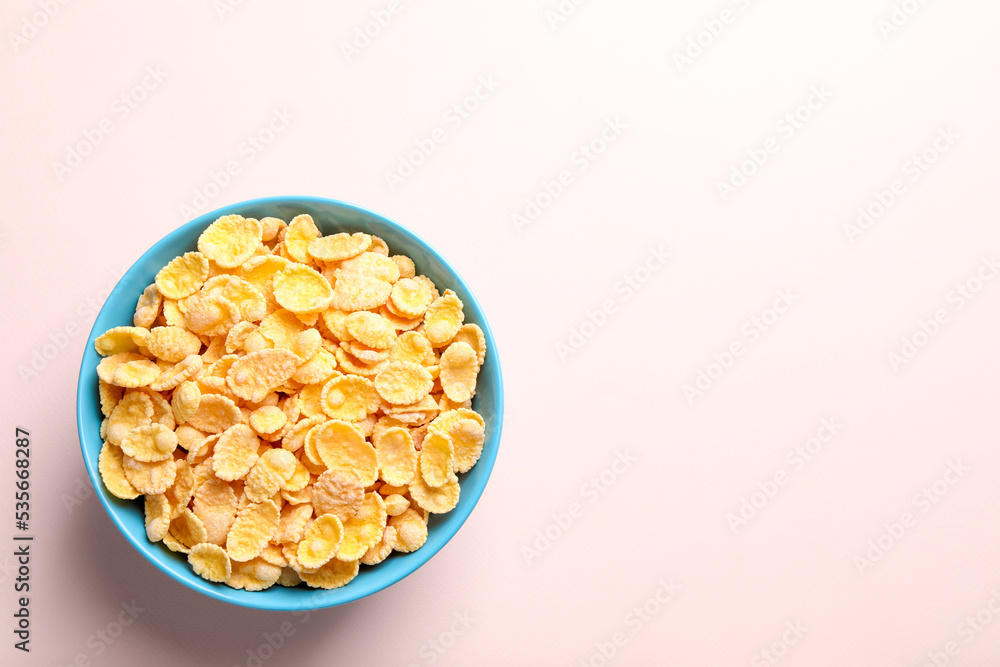 Bowl of tasty crispy corn flakes on light background, top view. Space for text
