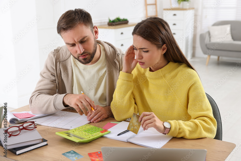 Young couple discussing family budget at table in living room Young couple discussing family budget at table in living room
