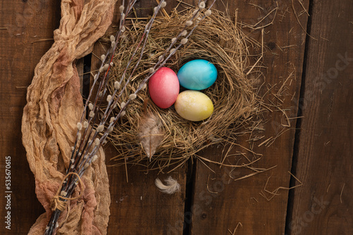 Painted Easter chicken eggs in a nest and willow branches. Holiday Easter concept background. High quality photo