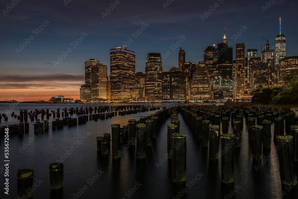 New York City skyline at twilight and sunset with skyscraper lights and piers and piles