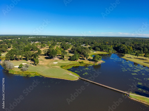 an aerial shot of a gorgeous autumn landscape on Houston Lake with rippling blue water surrounded by lush green trees, grass and plants and homes with a gorgeous clear blue sky in Perry Georgia USA photo