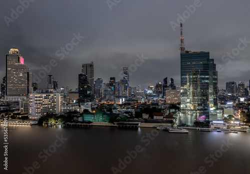 Photography Bangkok, thailand - Aug 22, 2022 : Skyscrapers in the business district along chaopraya river of Bangkok city at night under Sprinkling rain