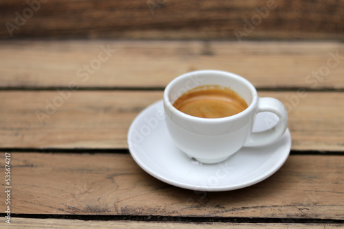 Espresso coffee in white ceramic cup on wooden table background. Espresso can be made with a wide variety of coffee beans and roast degrees.