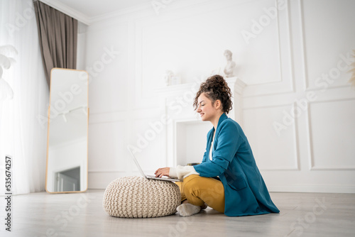 one woman young adult use computer while sitting on the floor at home