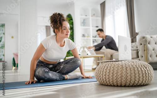 Young woman online yoga training class at home on laptop computer