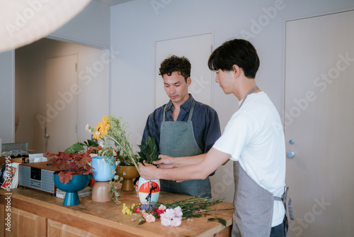 カウンターで花を生ける二人の男性