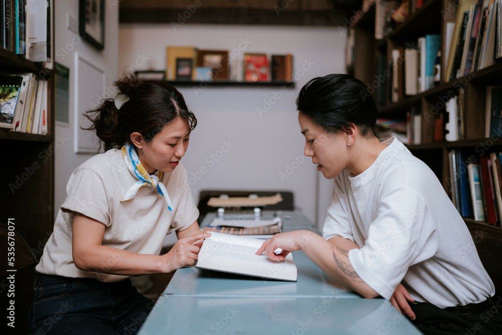 机に本を広げて読む二人の女性 机に本を広げて読む二人の女性