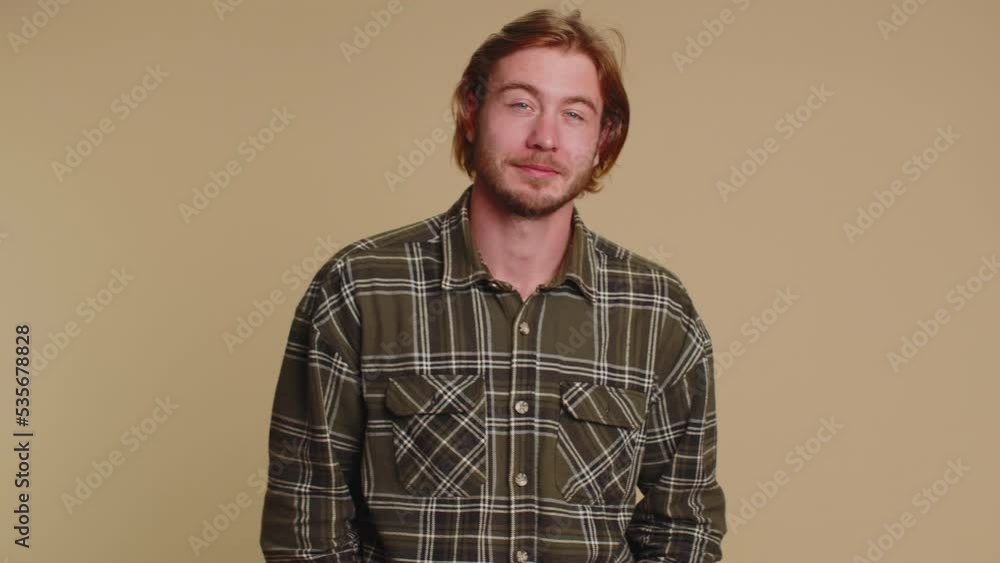 Smiling playful happy man in shirt blinking eye, looking at camera with toothy smile winking and flirting, expressing optimism. Young handsome adult guy alone isolated on beige wall background Smiling playful happy man in shirt blinking eye, looking at camera with toothy smile winking and flirting, expressing optimism. Young handsome adult guy alone isolated on beige wall background