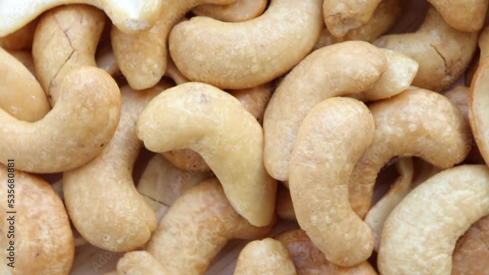 Close up of cashew nuts pattern texture. Cashew nuts full macro shoot rotating on wooden background. rotating, turning, top view. Close up of cashew nuts pattern texture. Cashew nuts full macro shoot rotating on wooden background. rotating, turning, top view.