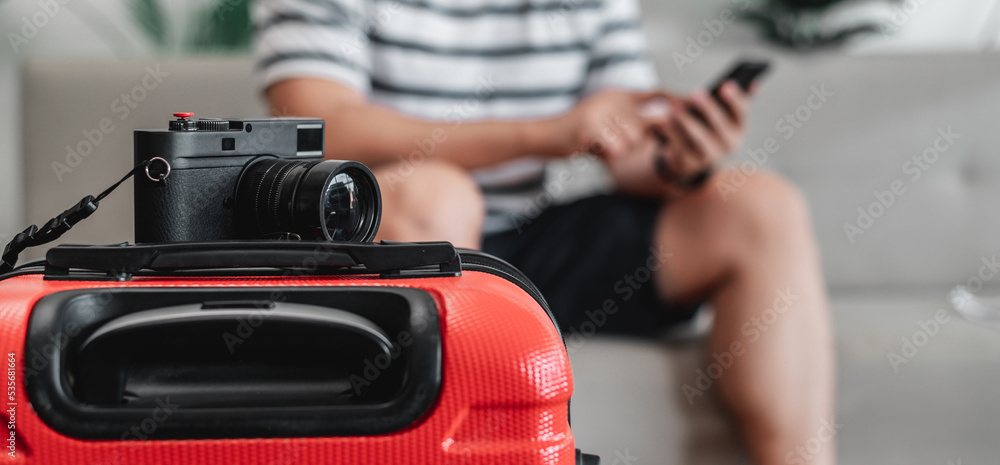 Close-up of Retro camera on luggage with traveler man sitting on sofa background