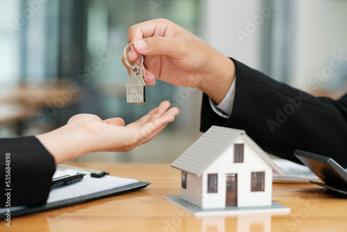 Real estate agent giving house keys to client after signing contract.