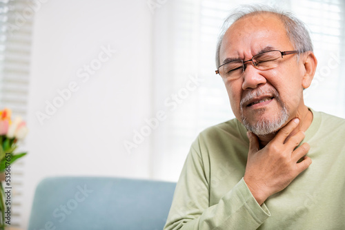Asian old man painful in the sore throat, retirement senior man feeling pain use hands holding neck, Elderly people have dysphagia due to eating, Health care and medicine concept photo