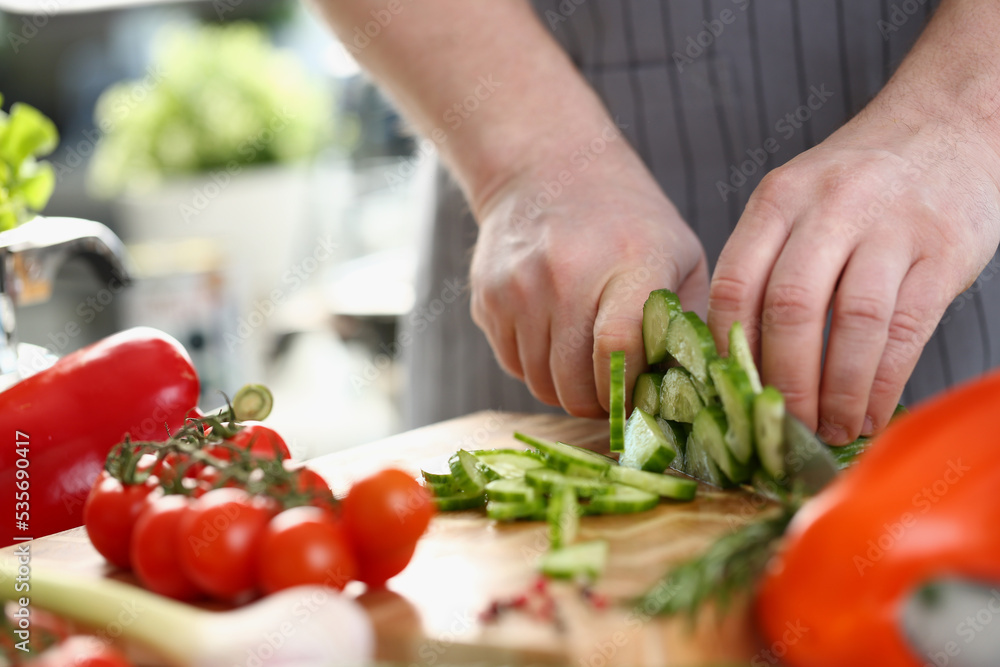 Green cucumbers are cut with knife in kitchen Green cucumbers are cut with knife in kitchen
