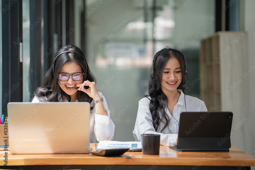 Beautiful smiling female call center worker accompanied by her team working in the office. Beautiful smiling female call center worker accompanied by her team working in the office.
