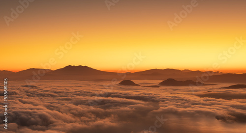 夜明けの空を背景にした山々のシルエットと雲海の広がる風景。北海道の津別峠。