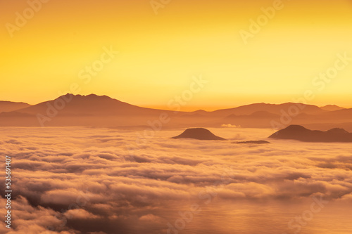 夜明けの空を背景にした山々のシルエットと雲海の雄大な風景。北海道の津別峠。