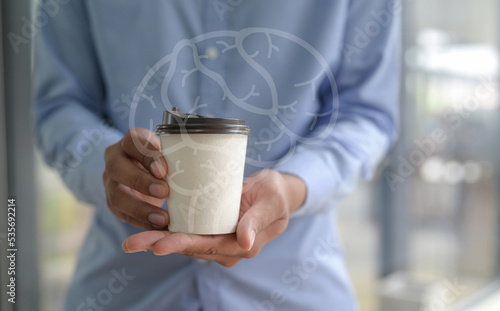 Close-up of barista holding coffee cup in hand with brain hologram, coffee affects brain.