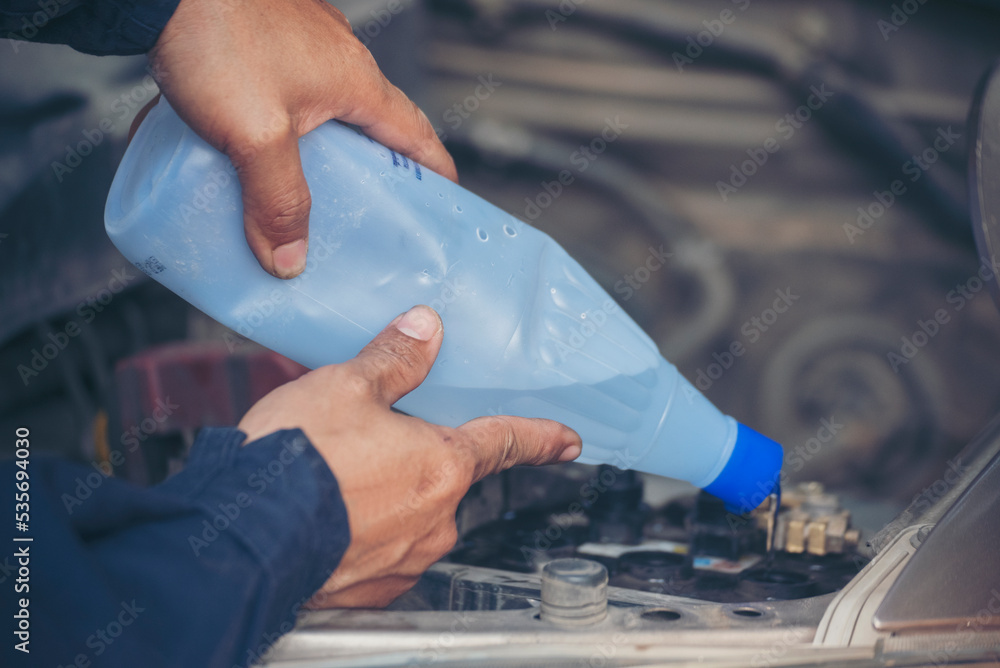 Car Mechanic man hands pouring Deionized purified Distilled water for