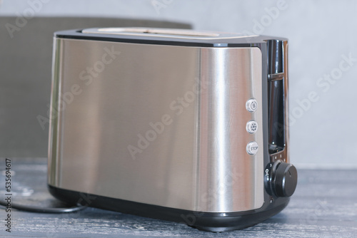 modern electric metallictoaster on grey wooden table in kitchen. electrical appliances for cooking