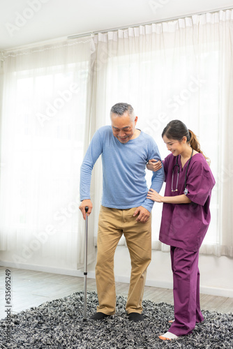 Medical worker helping her patient to move around the home. Gentle trained nurse helping mature patient. Recovery process.