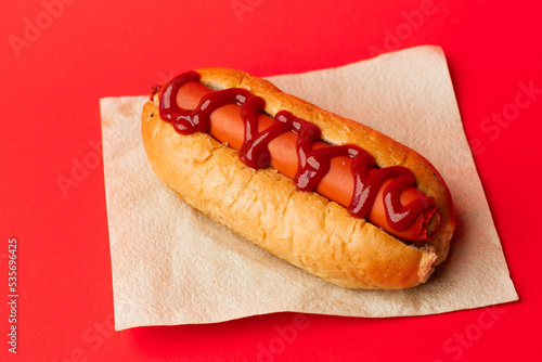American Hotdog with drizzle of sauce on napkin sitting on red background