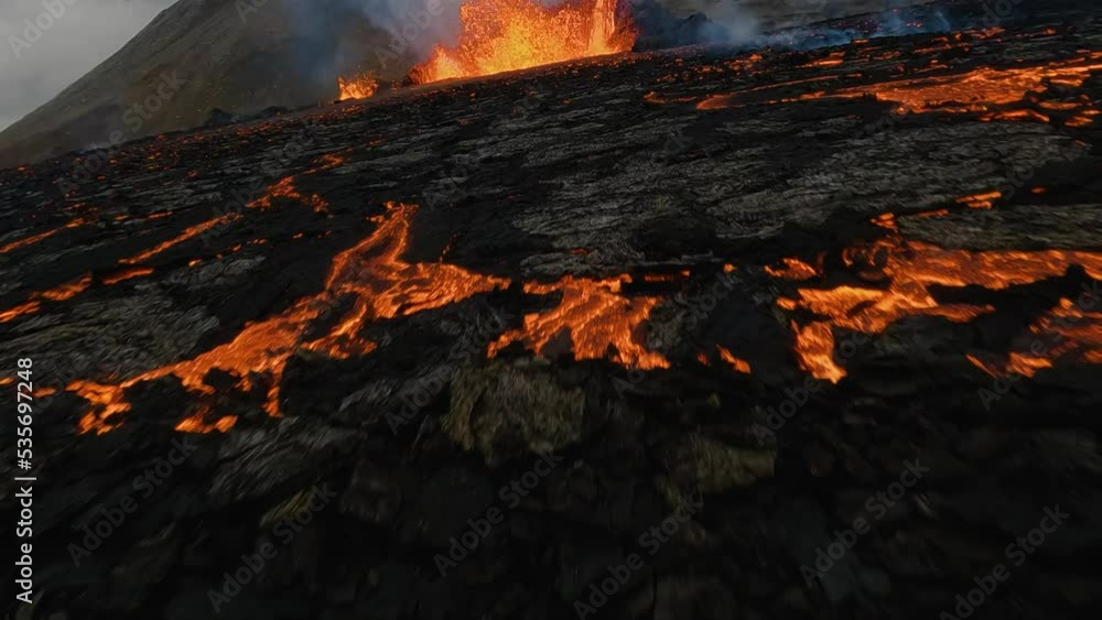 FPV drone shot over molten rock, through a exploding orange red lava abyss - slow motion FPV drone shot over molten rock, through a exploding orange red lava abyss - slow motion