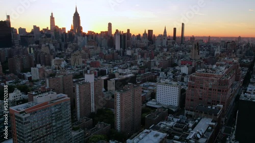 An aerial time-lapse from a park in Manhattan, facing northeast at sunrise. The camera boom straight up to reveal the New York City skyline with the Empire State Building in front of the sun. photo