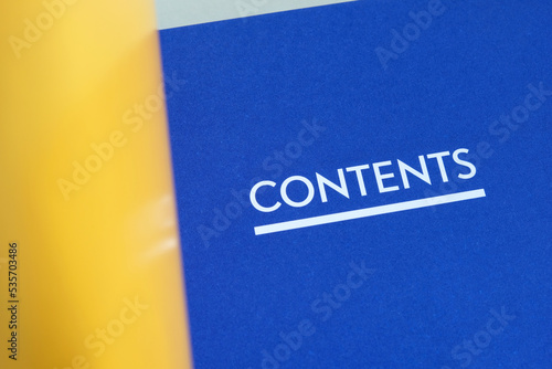 The word 'Contents' printed on the first pages of an annual report listing chapters and sections of the book. A book opened to the table of content page. Closeup macro view. photo