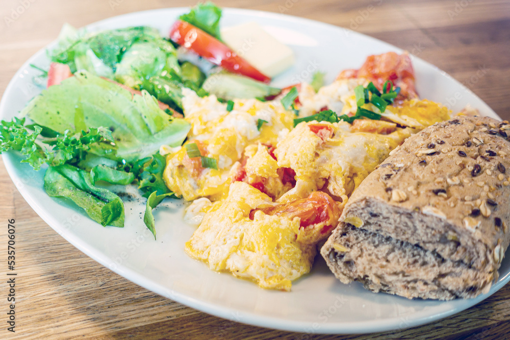 Omelet cooked with tomatoes and chives prepared with fresh lettuce as side dishes for a healthy vegetarian breakfast ready to be served