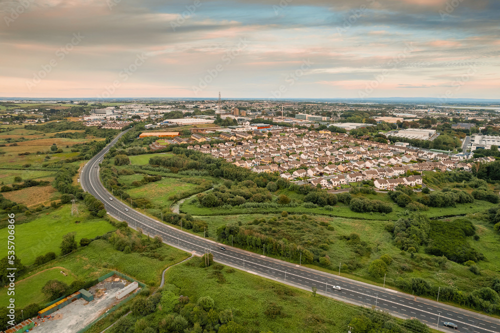 Aerial view on a city residential area with houses and park and highway. Galway, Ireland. Blue cloudy sky. High density urban land.