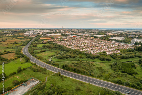 Aerial view on a city residential area with houses and park and highway. Galway, Ireland. Blue cloudy sky. High density urban land.