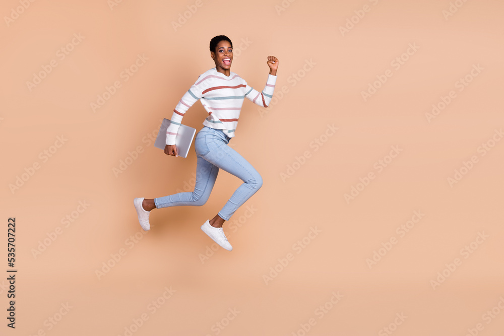 Photo of charming sweet unisex person wear sweater running jumping holding device isolated beige color background