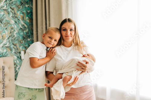 Lifestyle family portrait of parents with newborn baby child and older son. Happiness and love at home indoors