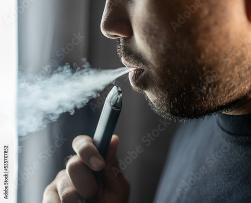 Close-up mouth of man smoke inhaling, breathing and smoke electronic cigarette. photo