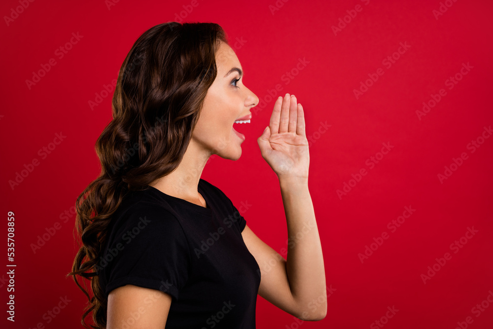 Photo of pretty shiny young lady dressed black t-shirt smiling arm lips making announcement empty space isolated red color background Photo of pretty shiny young lady dressed black t-shirt smiling arm lips making announcement empty space isolated red color background