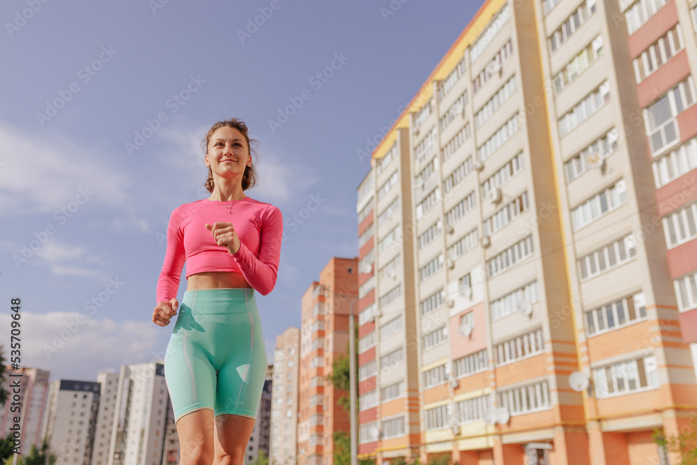 sports girl in bright sportswear runs in the city