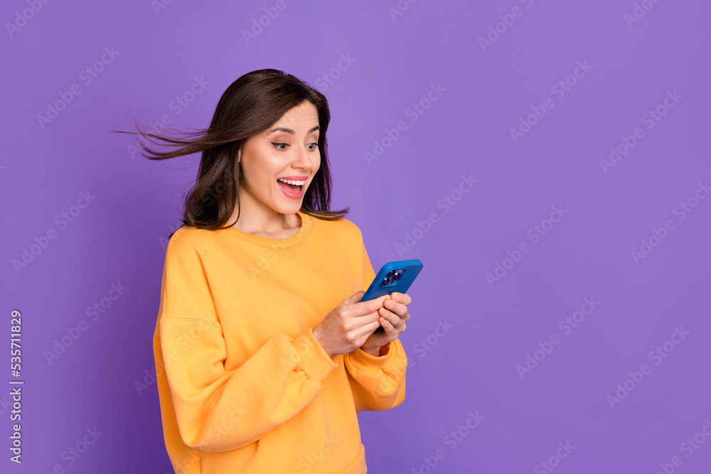 Photo of young attractive gorgeous nice lady wear yellow sweater shocked hold phone good advert eshopping offer isolated on purple color background Photo of young attractive gorgeous nice lady wear yellow sweater shocked hold phone good advert eshopping offer isolated on purple color background