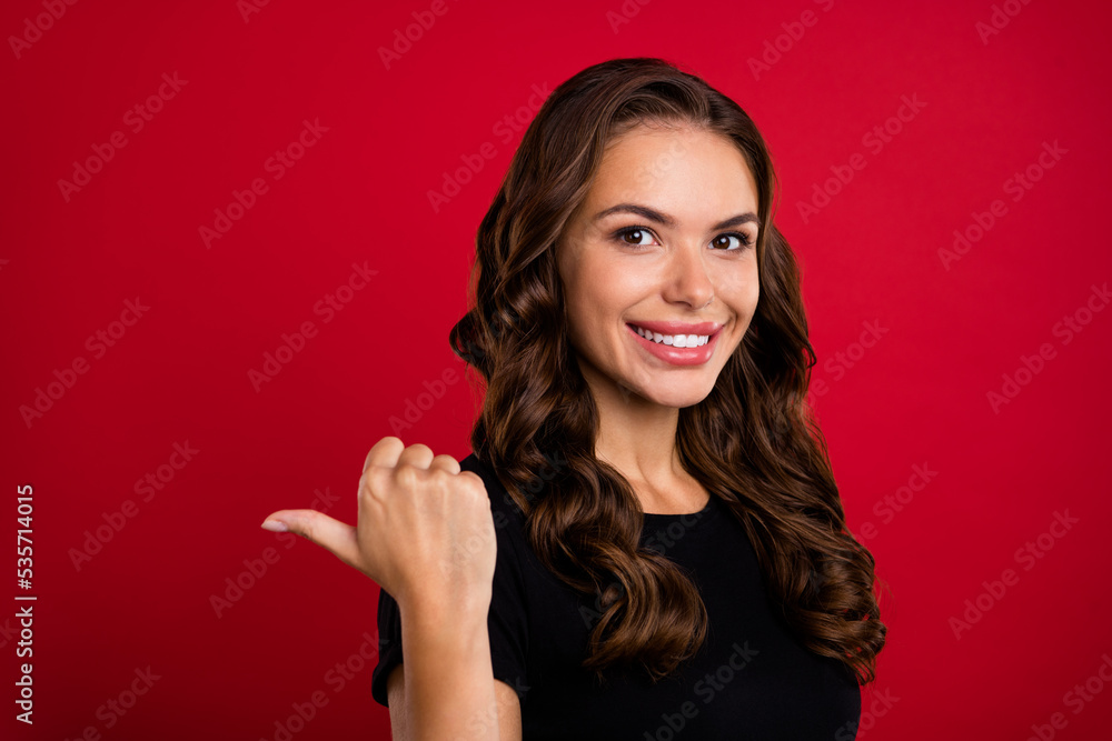 Photo of pretty cute young lady dressed black t-shirt smiling pointing finger back empty space isolated red color background Photo of pretty cute young lady dressed black t-shirt smiling pointing finger back empty space isolated red color background