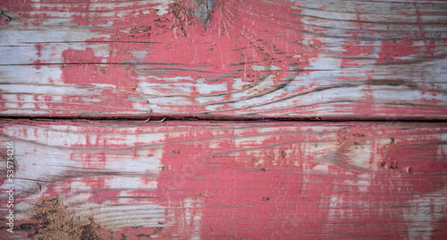 Color peels from the texture of the red painted wood surface