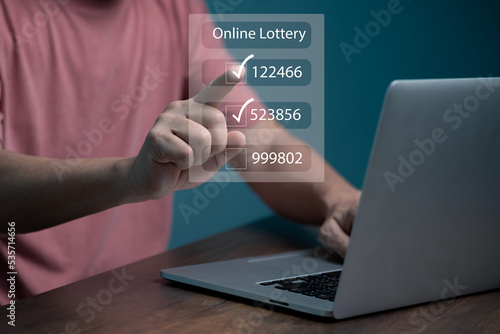 Man using computer and touching on virtual Online lottery screen to buy two number set. 