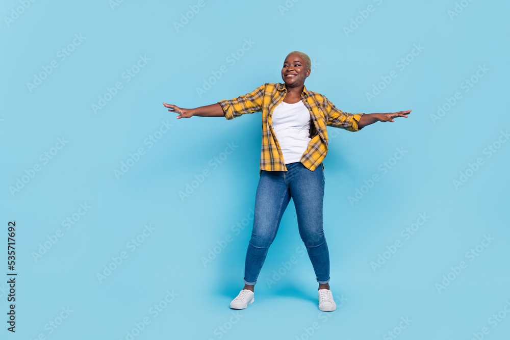 Full length photo of funky dreamy woman dressed plaid shirt dancing arms sides isolated blue color background Full length photo of funky dreamy woman dressed plaid shirt dancing arms sides isolated blue color background