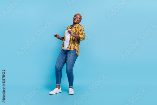 Full length photo of attractive funky woman dressed plaid shirt dancing having fun isolated blue color background
