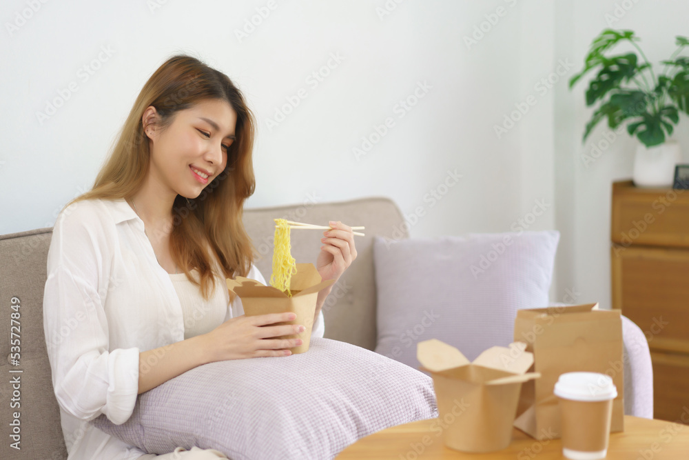 Work from home concept, Businesswoman using chopsticks and eating instant noodles in living room Work from home concept, Businesswoman using chopsticks and eating instant noodles in living room