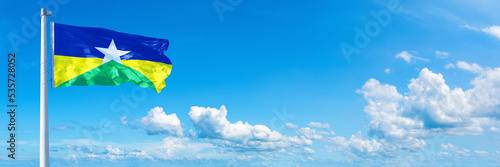 Rondônia - state of Brazil, flag waving on a blue sky in beautiful clouds - Horizontal banner photo